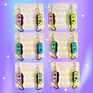 Puede incluir: Seis pares de pendientes de mando de Nintendo Switch de colores. Cada par presenta una combinación de colores diferente, incluyendo rosa y amarillo, verde y azul, y rosa y verde.
