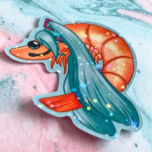 Op de afbeelding: Een holografische sticker van een garnaal met tealblauw haar en een roze hoofdband. De garnaal is oranje en heeft een glinsterende afwerking.