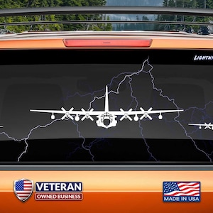 May include: White vinyl decal of a C-130 Hercules aircraft with lightning bolts in the background. The decal is on the back window of a truck. The text "LIGHTNING NOT INCLUDED" is at the top of the decal. The text "VETERAN OWNED BUSINESS" is on the truck. The text "MADE IN USA" is on the truck. The text "www.fegraphics.com Flight Engineered Graphics Aircraft Decals" is at the bottom of the image. The text "VETERAN OWNED BUSINESS" is at the bottom of the image.