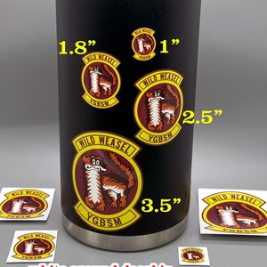 May include: A black stainless steel water bottle with a handle. The bottle has several decals of a cartoon weasel with the text "Wild Weasel" and "YGBSM". The decals are available in different sizes: 1 inch, 1.8 inches, 2.5 inches, and 3.5 inches.