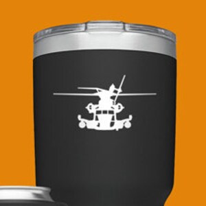 May include: Set of four Yeti tumblers with a helicopter silhouette design. The tumblers are in black, green, blue, and silver. The tumblers are all different sizes. The tumblers have the Yeti logo on the bottom.