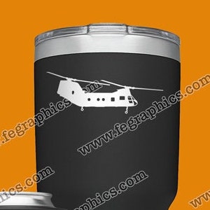 May include: A set of four insulated tumblers with a silhouette of a helicopter on each. The tumblers are in black, green, blue, and silver. The tumblers are all the same size and shape. The tumblers are all decorated with the same helicopter silhouette. The tumblers are all decorated with the same website address: www.fegraphics.com. The tumblers are all decorated with the same text: Flight Engineered Graphics. The tumblers are all decorated with the same text: Veteran Owned Business. The tumblers are all decorated with the same text: Aircraft Decals. The tumblers are all decorated with the same text: Every Decal is Hand Made to order by me, NATE.