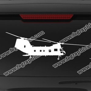 May include: A white silhouette of two helicopters on a black car window. The car window has a website address printed on it. The website address is www.fegraphics.com. Below the image of the helicopters is a white banner with the text "Flight Engineered Graphics" and a logo of a winged aircraft. Below the banner are two logos, one with the text "VETERAN OWNED BUSINESS" and a shield with an American flag, and the other with a winged aircraft. Below the logos is the text "Aircraft Decals". Below the text is a white banner with the text "Every Decal is Hand Made to order by me, NATE."