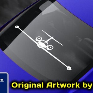 May include: A white decal of a small airplane on a blue car window. The decal is for sale on the website www.fegraphics.com. The text "Flight Engineered Graphics" and "Original Artwork by NATE" is also visible on the image.