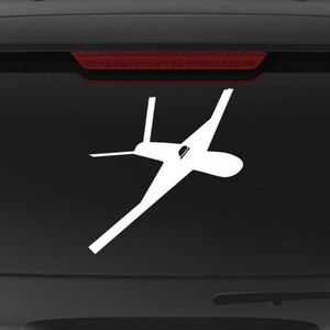 May include: A black SUV with a white silhouette of a drone on the back window. The vehicle has a "Veteran Owned Business" sticker on the back bumper.