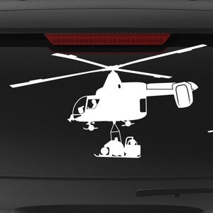 May include: A black SUV with a white silhouette of a helicopter on the back window. The vehicle has a "Veteran Owned Business" sticker on the back bumper.