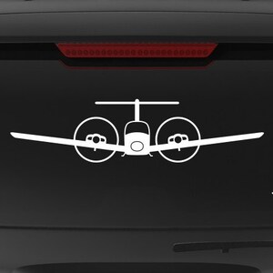 May include: A black SUV with a white decal of a twin-engine airplane on the back window. The decal is centered on the window and is slightly larger than the "Veteran Owned Business" sticker below it.