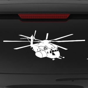 May include: A black SUV with a white silhouette of a helicopter on the back window. The vehicle has a "Veteran Owned Business" sticker on the back bumper.