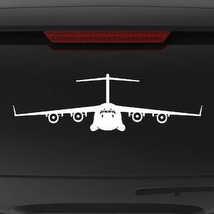 May include: White vinyl decal of a C-17 Globemaster III military transport aircraft. The decal is displayed on the rear window of a black SUV. A smaller version of the aircraft is also present. The text "VETERAN OWNED BUSINESS" is also visible.