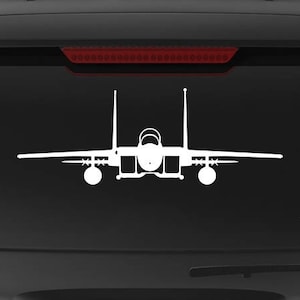 May include: A black SUV with a white silhouette of an F-15 Eagle fighter jet on the back window. The vehicle has a "Veteran Owned Business" sticker on the rear bumper.