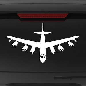 May include: A black SUV with a white silhouette of a B-52 bomber on the back window. The vehicle has a "Veteran Owned Business" sticker on the back bumper.