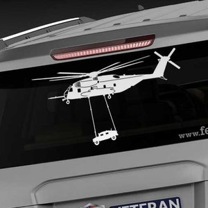 May include: A white vinyl decal of a helicopter carrying a vehicle, affixed to the rear window of a silver SUV. The decal includes the text "www.fegraphics.com" and a "Veteran Owned Business" sticker.