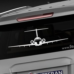 May include: A gray SUV with a white airplane silhouette decal on the rear window. The decal is centered on the window and has the text "www.fegraphics.com" below it. The SUV also has a sticker that says "Veteran Owned Business" with an American flag.