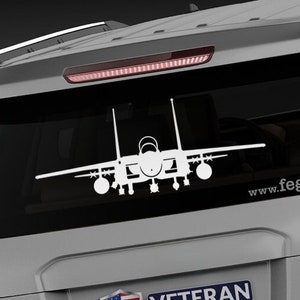 May include: A white silhouette of an F-15 Eagle fighter jet on the back window of a gray SUV. The vehicle has a "Veteran Owned Business" sticker and the website "www.fegraphics.com" printed on the back.