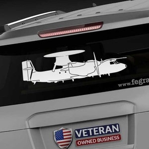 May include: A gray SUV with a white silhouette of a plane on the back window. The plane has a propeller and a radar dish on top. The SUV has a "Veteran Owned Business" sticker with an American flag on the back. The text "www.fegraphics.com" is printed on the back of the SUV.