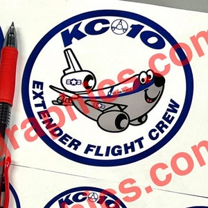 May include: Four round stickers with a blue border and white background. Each sticker features a cartoon airplane with a smiling face and the text "KC10 EXTENDER FLIGHT CREW".