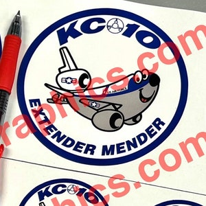 May include: Four round stickers with a cartoon airplane design. The stickers are white with blue and gray accents. The text on the stickers reads "KC-10 Extender Mender".