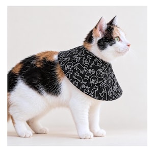 May include: A calico cat wearing a black fabric recovery collar featuring a repeating white line art pattern of various cat silhouettes. The collar is cone-shaped and fits snugly around the neck, providing a protective barrier for the feline.