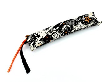 May include: A black and white cat toy with an orange string. The toy is shaped like a long tube and is covered in a fabric with a pattern of stars, moons, and other mystical symbols. The text "Moon Cat" is printed on the toy.