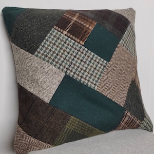 May include: A patchwork pillow cover with a geometric design featuring various shades of green, brown, and beige. The pillow cover is made of a soft, textured fabric.