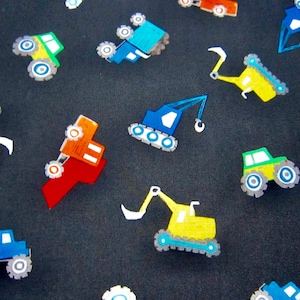 May include: A black fabric with a repeating pattern of colorful toy construction vehicles. The vehicles include dump trucks, cranes, and monster trucks. The vehicles are in shades of blue, yellow, red, green, and orange.