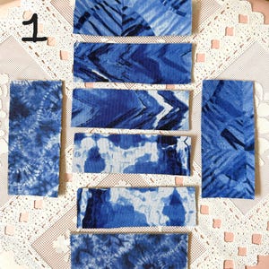 May include: An assortment of blue and white tie-dye fabric swatches. The swatches are rectangular and feature various patterns, including stripes and swirls. The number "1" is written in black on the upper left corner.