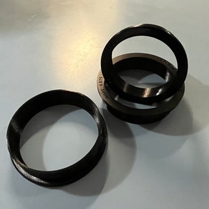 Może przedstawiać: Trzy czarne plastikowe pierścienie, jeden z nadrukiem "HORE 4.075" na boku.