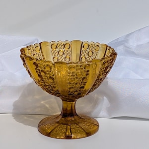 May include: A vintage amber glass candy dish with a pedestal base and a textured, bubbled design.