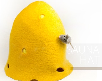 Peut inclure: Un chapeau de sauna en feutre jaune avec des trous sur le côté. Une petite souris en feutre gris sort du côté du chapeau. Le texte "SAUNA HAT" est visible en arrière-plan.