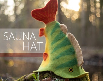 Peut inclure: Un chapeau de sauna fantaisiste en forme de poisson, avec une queue et des nageoires rouges, et un corps vert et jaune. Le chapeau porte l'inscription "SAUNA HAT" en blanc. Le chapeau est en feutre et repose sur une surface moussue.