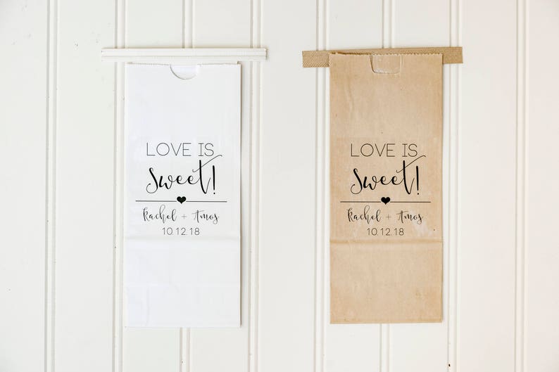 May include: Two white and brown paper bags with a black and white design that says "Love is Sweet!" with the names Rachel and Timos and the date 10.12.18 printed on them.