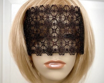 May include: A black lace eye mask with a delicate floral pattern. The mask is made of a soft, sheer fabric and has a slightly shimmery finish.