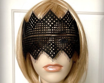 May include: A black lace eye mask with a scalloped edge. The mask is made of delicate, intricate lace and has a geometric pattern.