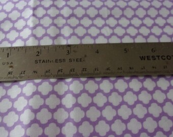May include: A close-up of a silver ruler with black markings. The ruler is labeled "STAINLESS STEEL" and "WESTCOTT". The ruler is placed on top of a purple fabric with a white pattern.