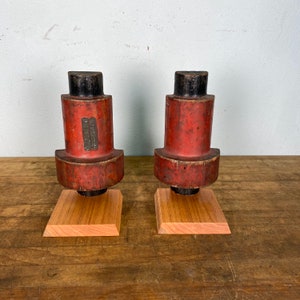 May include: Two antique wooden blocks with black tops and red bases. The blocks are sitting on wooden bases. The blocks have a label on the side that reads "C.W. BREWER & CO.  NEW YORK."
