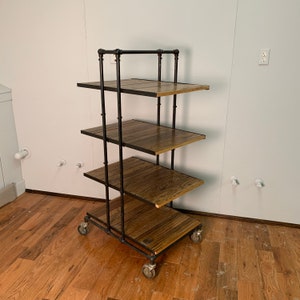 May include: A black metal industrial style shelving unit with four wooden shelves and wheels. The shelves are made of reclaimed wood with a natural finish.