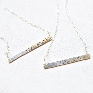 May include: Two silver necklaces with hammered metal bar pendants. The top pendant says "stay salty" and the bottom pendant says "live aloha".