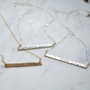 May include: Three silver necklaces with hammered bar pendants. The pendants are engraved with the phrases "Live Aloha", "Live Aloha", and "Salty Girl".