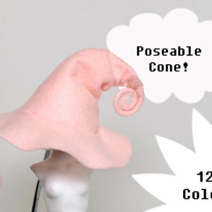 May include: A light pink witch hat with a curled tip, displayed on a mannequin head. The hat has a wide brim and a tall, pointed crown. Text on the image reads "Poseable Cone!" and "12+ Colors".