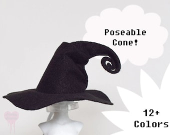 Puede incluir: Un sombrero de bruja negro con ala ancha y punta rizada y ajustable. El texto "Poseable Cone!" y "12+ Colors" se muestra en blanco. El sombrero se exhibe en una cabeza de maniquí.