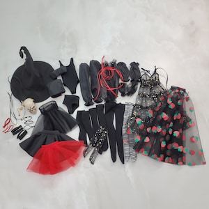 May include: A collection of doll clothing and accessories including a black witch hat, a skull, black leotards, skirts in black and red tulle, various black stockings, arm warmers, a black dress with gold stars, and a black skirt with red strawberry prints.