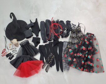 May include: A collection of doll clothing and accessories including a black witch hat, a skull, black leotards, skirts in black and red tulle, various black stockings, arm warmers, a black dress with gold stars, and a black skirt with red strawberry prints.