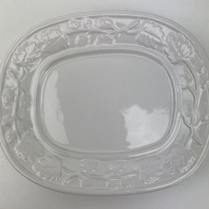 May include: White ceramic oval serving dish with a raised design of leaves and vines around the edge.