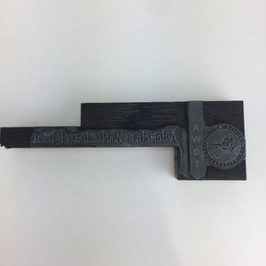 May include: A vintage wooden stamp with the text "Automotive Women of Texas" in a serif font. The stamp also features a circular emblem with a car and the text "A.W.O.T." and "TEXAS".