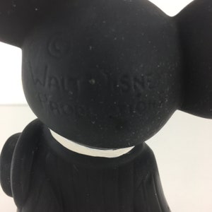 Op de afbeelding: Zwarte rubberen Mickey Mouse-figuur met een witte kraag. Het figuur heeft een copyright-symbool en de tekst "WALT DISNEY PRODUCTIONS" op de achterkant.