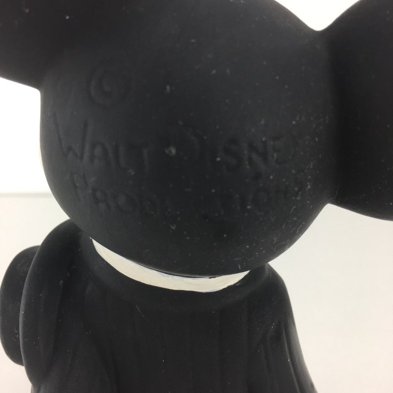 Op de afbeelding: Zwarte rubberen Mickey Mouse-figuur met een witte kraag. Het figuur heeft een copyright-symbool en de tekst "WALT DISNEY PRODUCTIONS" op de achterkant.
