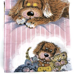 May include: A folded, rectangular, pink and white striped fabric with a cartoon illustration of a brown dog sleeping. Below, a brown dog, a grey cat, and a grey mouse are together.