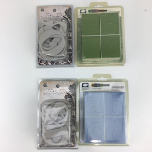 May include: Four packages of chipboard alphabet letters. Two packages are white with the text "[un]dressed" and the other two packages are green and blue with the text "Holly Dazzle" and "Meadow Collection".