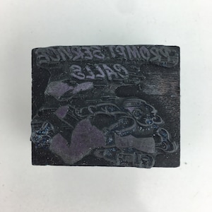 May include: A black rectangular woodcut block with the words "PROMPT SERVICE" and "GALLS" in reverse lettering. The block features a stylized image of a person running, with purple accents.