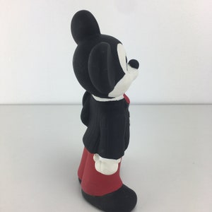 Op de afbeelding: Een zwart-witte keramische figuur van Mickey Mouse die een zwart pak en een rode broek draagt. Hij staat met zijn hoofd schuin.